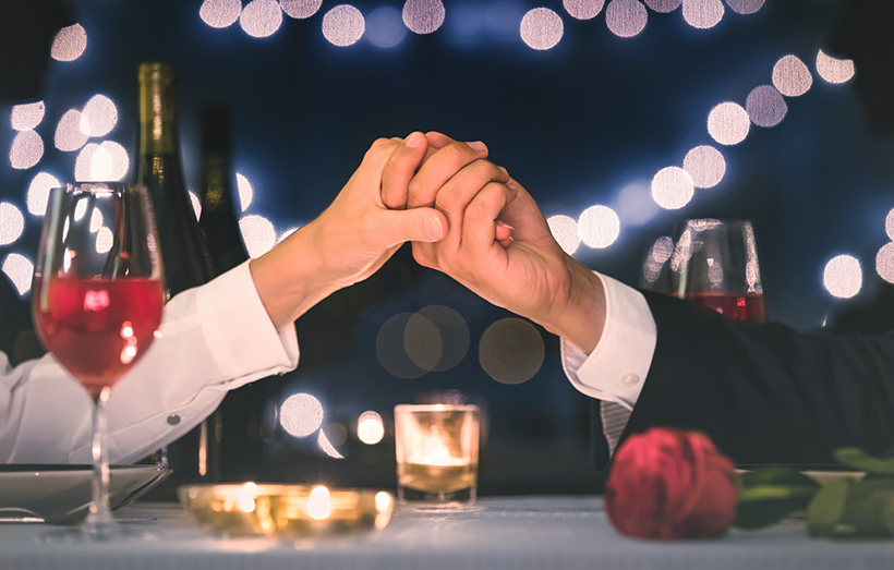 Couple holding hands at Valentine's Day dinner.