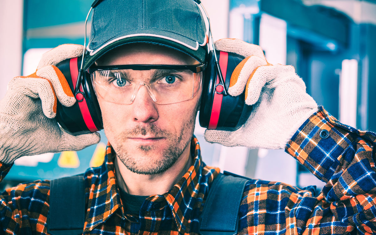 Man protects his hearing with earmuffs with bluetooth and radio capabilities.