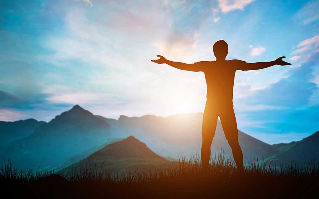 Person standing on the top of a mountain.