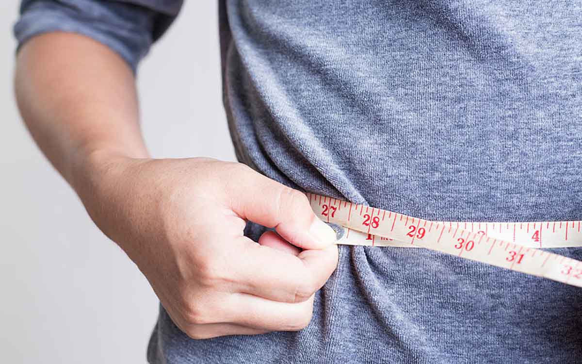 Man with a measuring tape around waist. How does your weight affect your hearing?