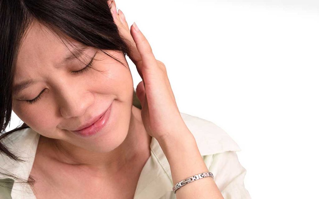 Woman with hand to her ear, suffering from Tinnitus and ringing in her ear.