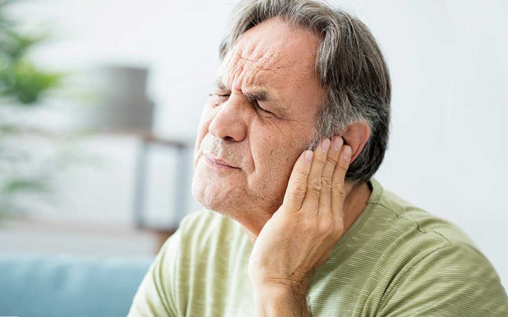 Man holding his ear because of Tinnitus
