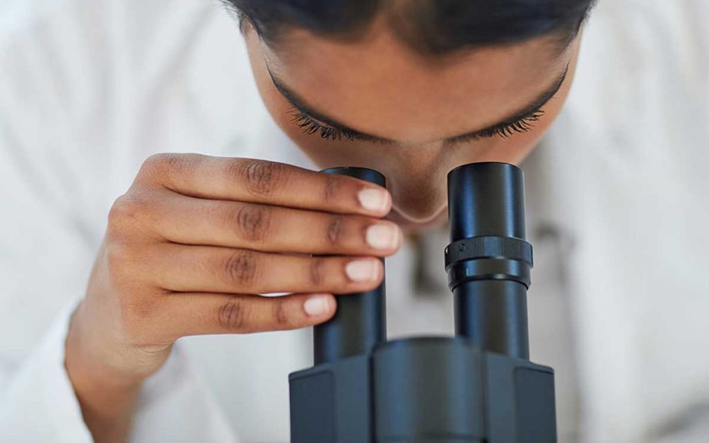 Scientist looking through microscope looking for hearing loss treatments.