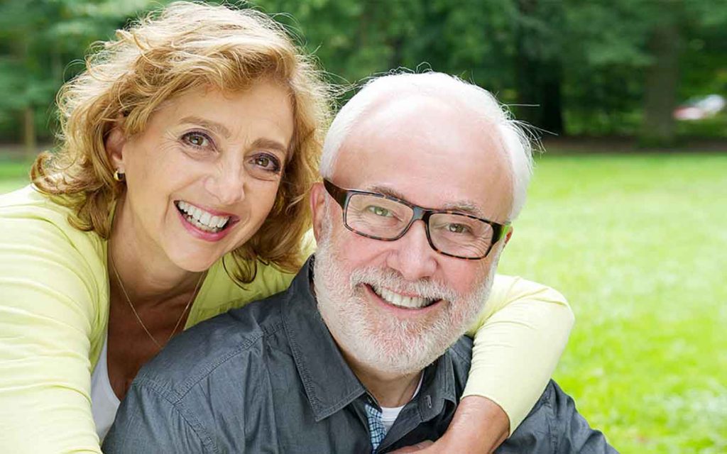 Happy middle aged couple wearing hearing aids.