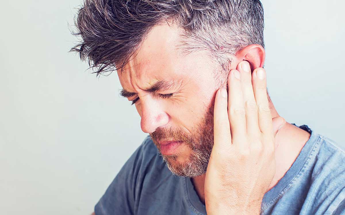 Man holding his ear because of Tinnitus ear pain.