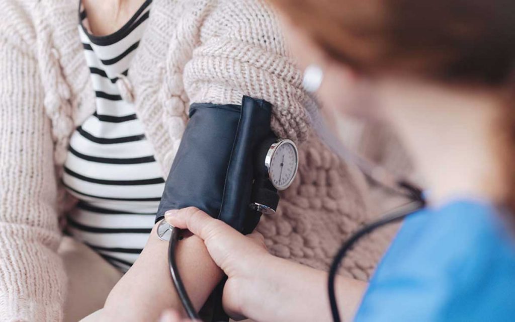 Woman getting blood pressure checked. Health problems and hearing loss.