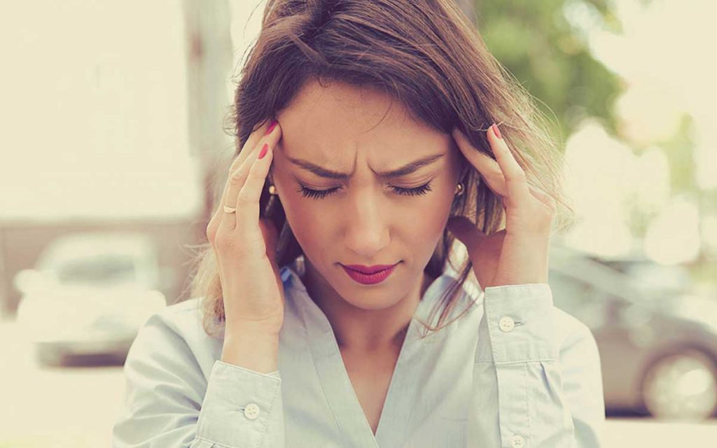 Woman holding her ears because of noise causing hearing loss.