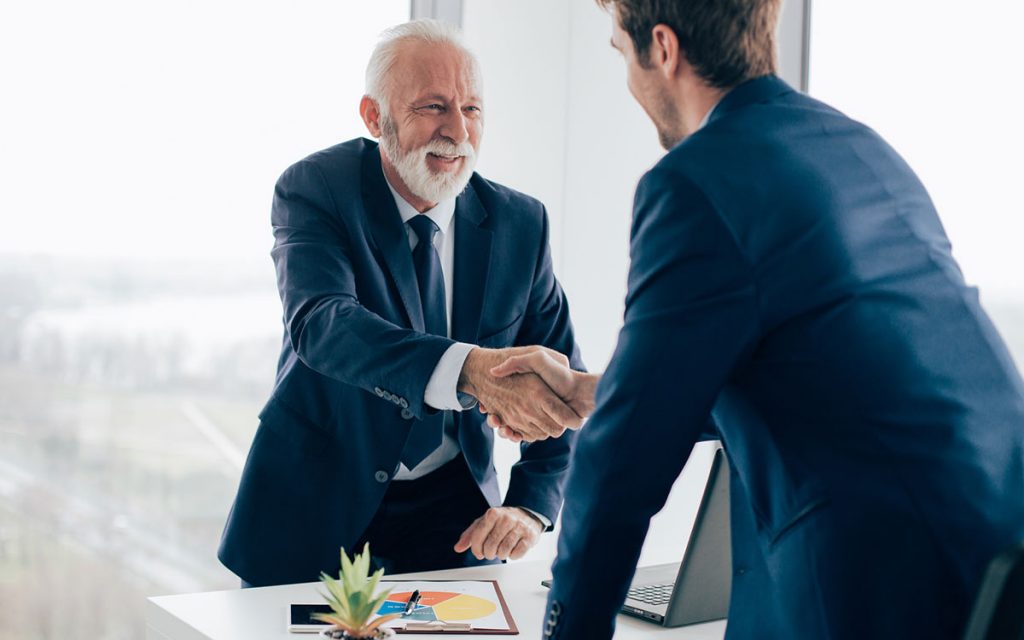 Business men shaking hands and successful because of hearing aids.