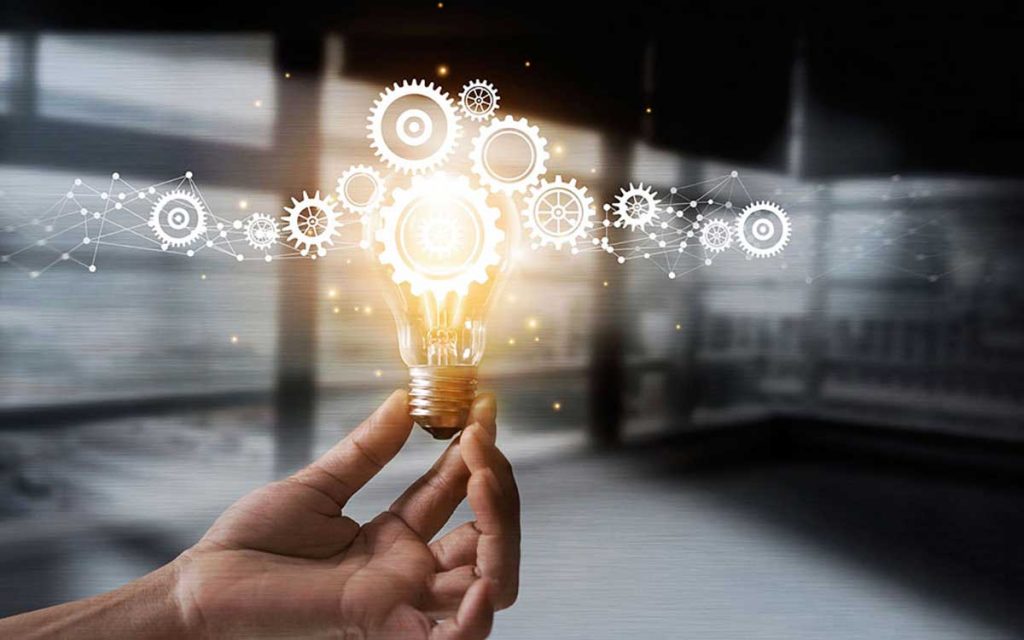 Hand holding a lightbulb representing hearing aid innovation.