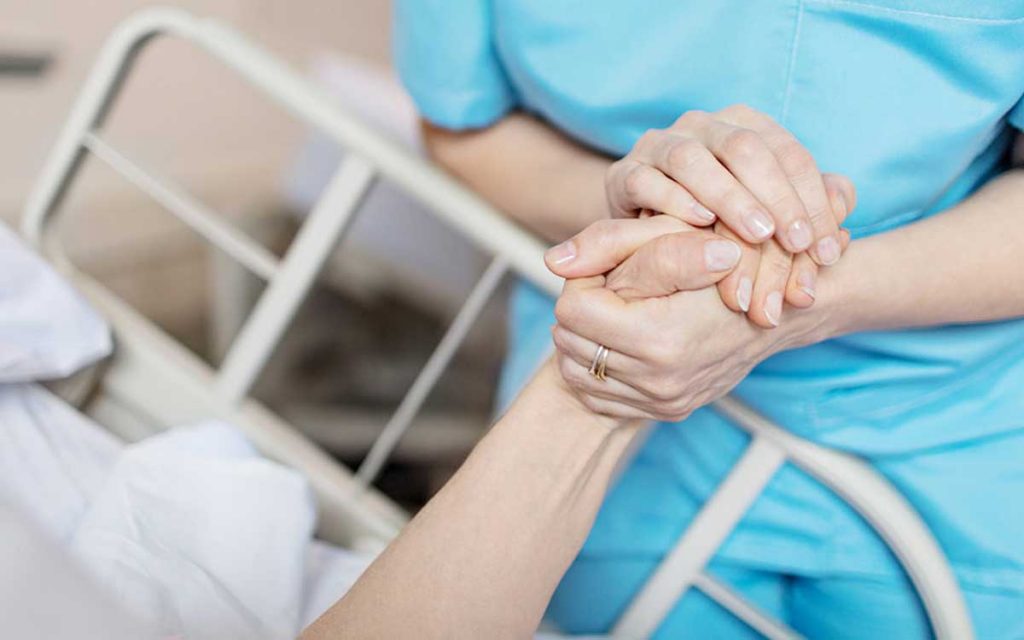 Woman holding hands of person who is in the hospital because of hearing loss.