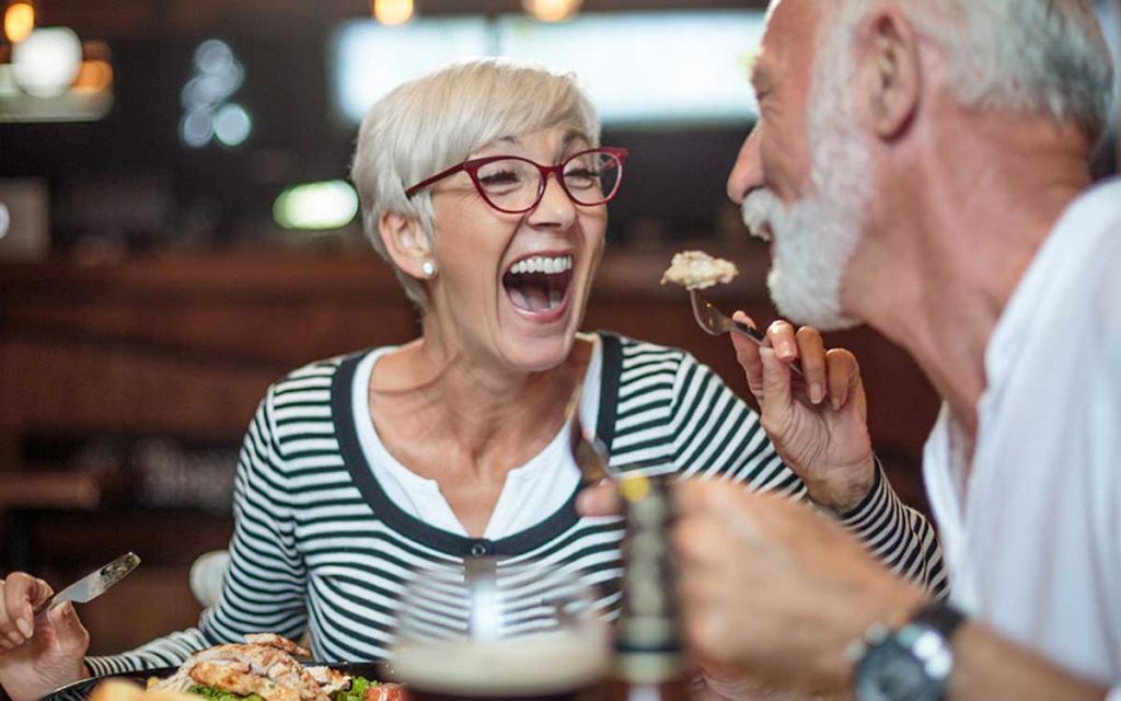 Two retired people having a conversation in a restaurant.