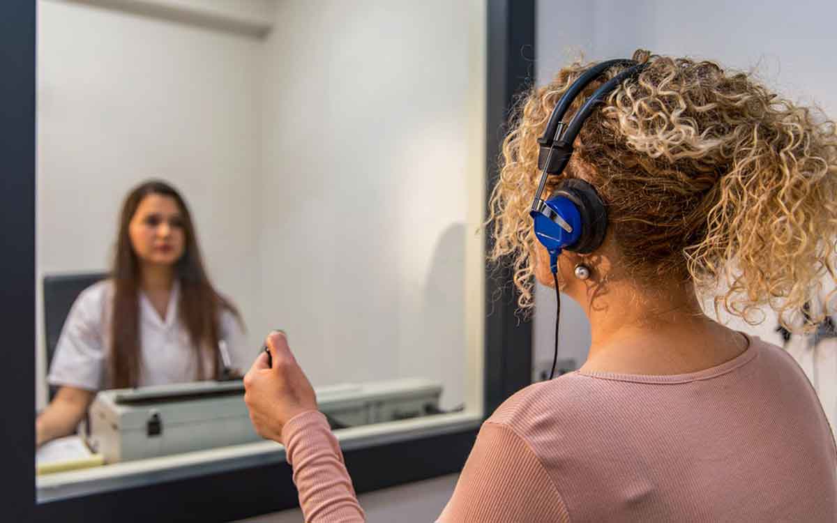 Woman in a booth getting a hearing test.