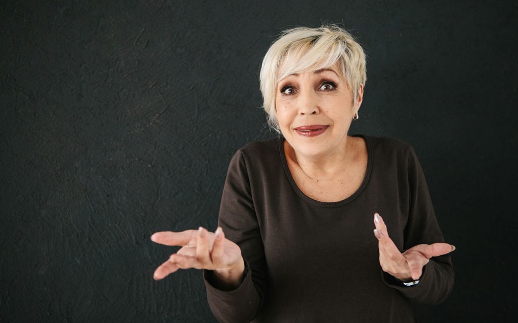 Woman shrugging her shoulders with questions about hearing aids.