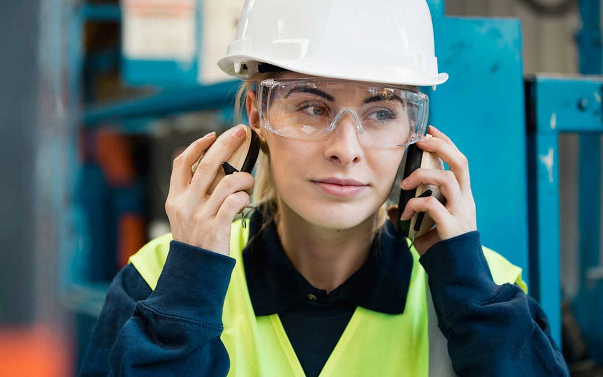 Woman construction worker putting on ear protection.
