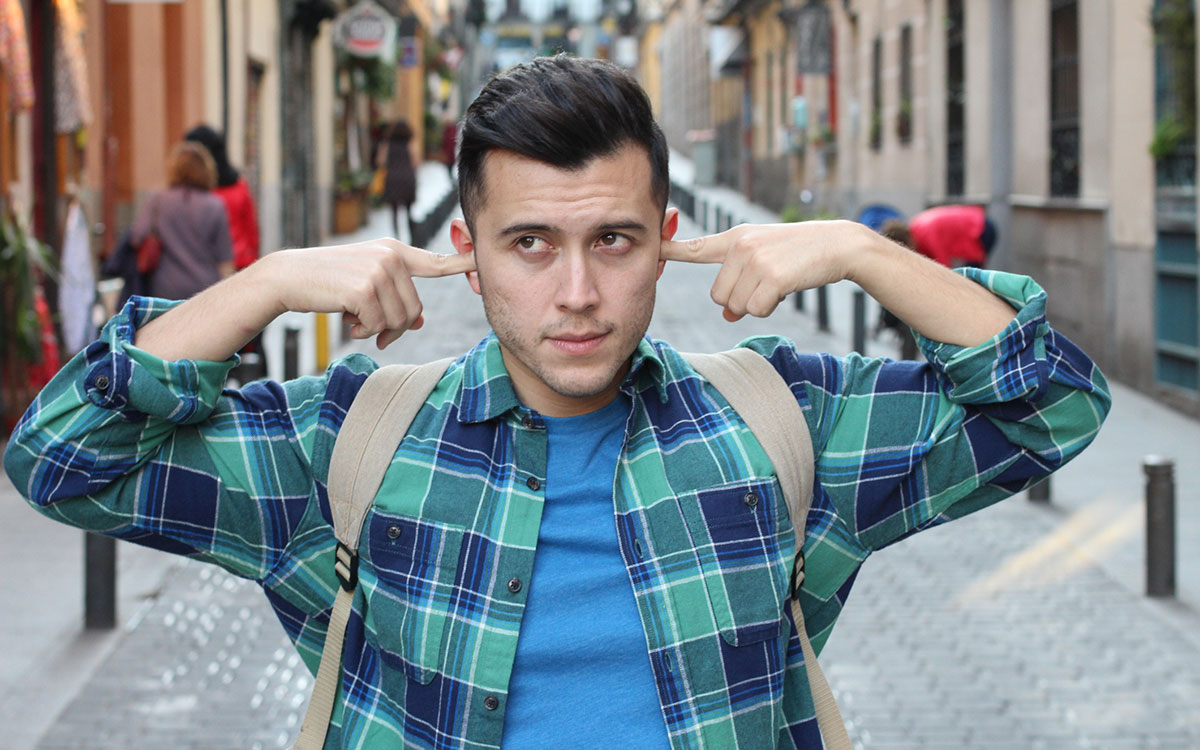 Man holding his ear because of noise pollution.