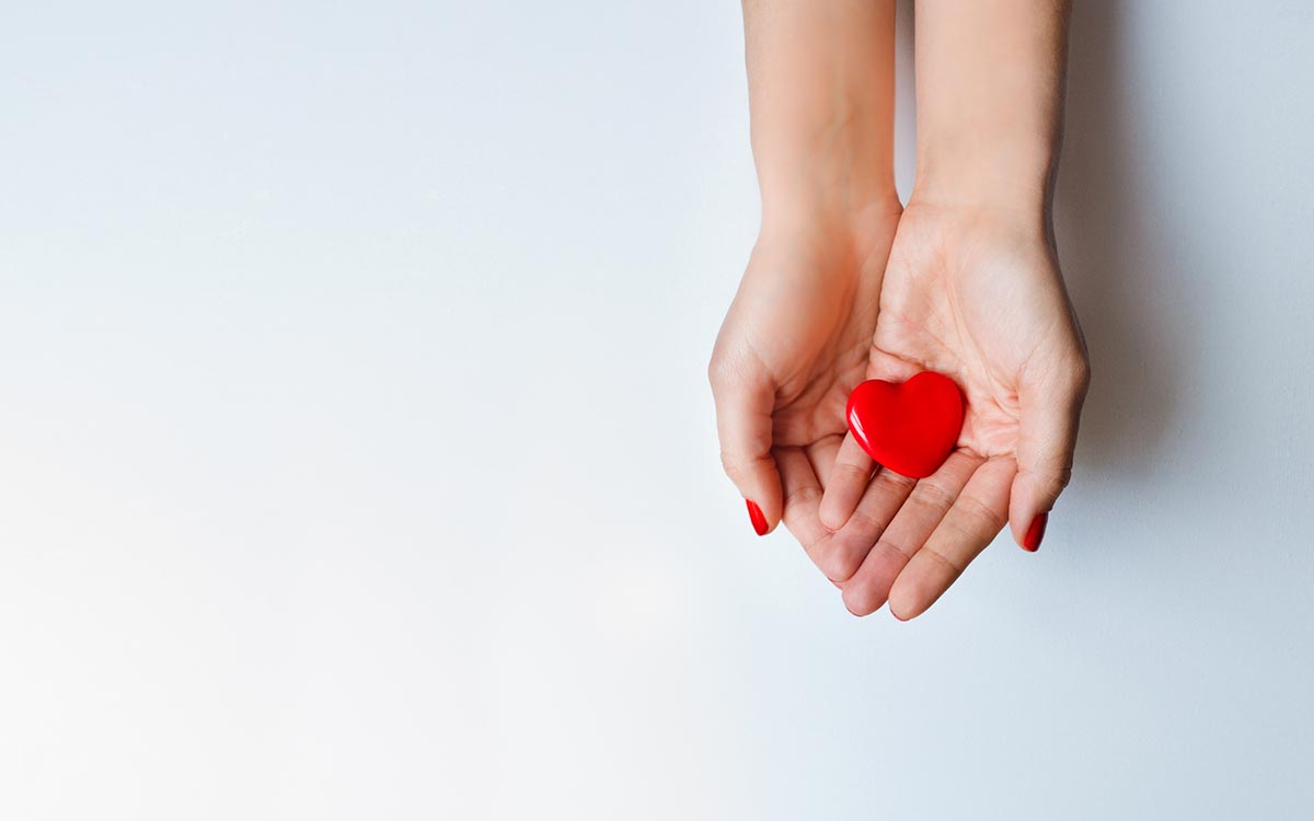 Hands holding a heart representing the benefits of hearing aids.