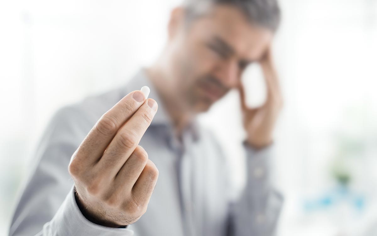 Man holding aspirin causing Tinnitus