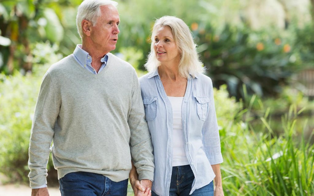 Middle aged couple walking and wondering if they should wear their hearing aid.