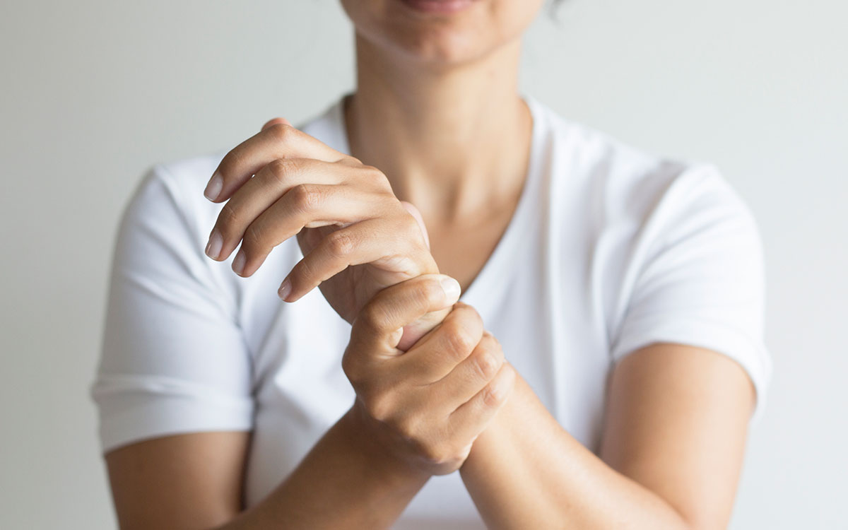 Woman holding her wrist becasue of inflammation. Hearing loss can come from inflammation.