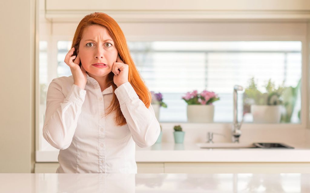 Woman holding her head unable to determine whether it's hyperacusis or misophonia.