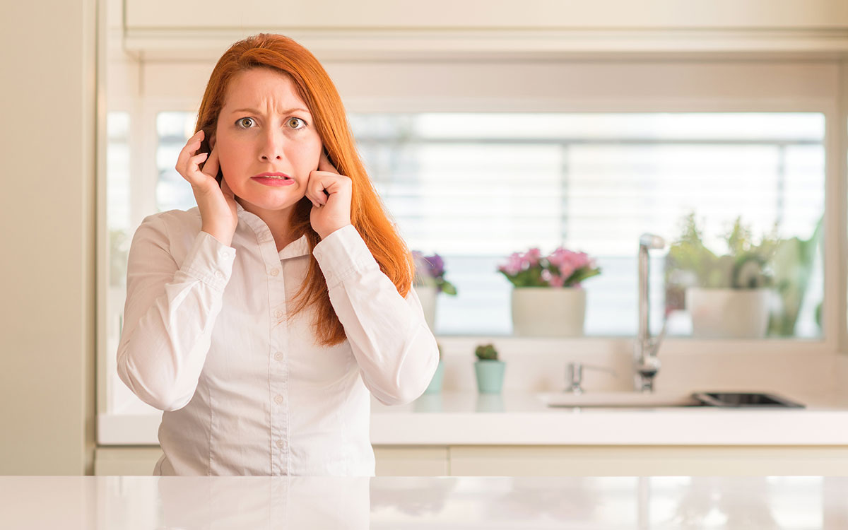 Woman holding her head unable to determine whether it's hyperacusis or misophonia.