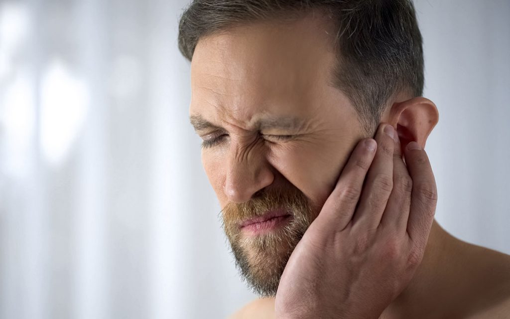 Man holding his ear because of sudden Sensorineural hearing loss