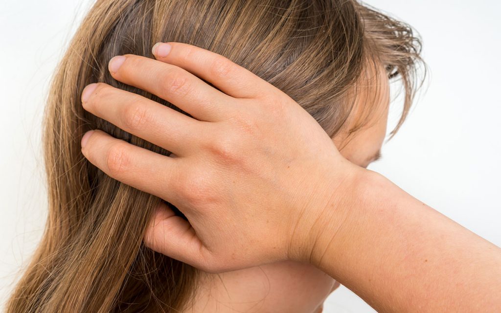 Woman holding her head because her environment is causing Tinnitus.