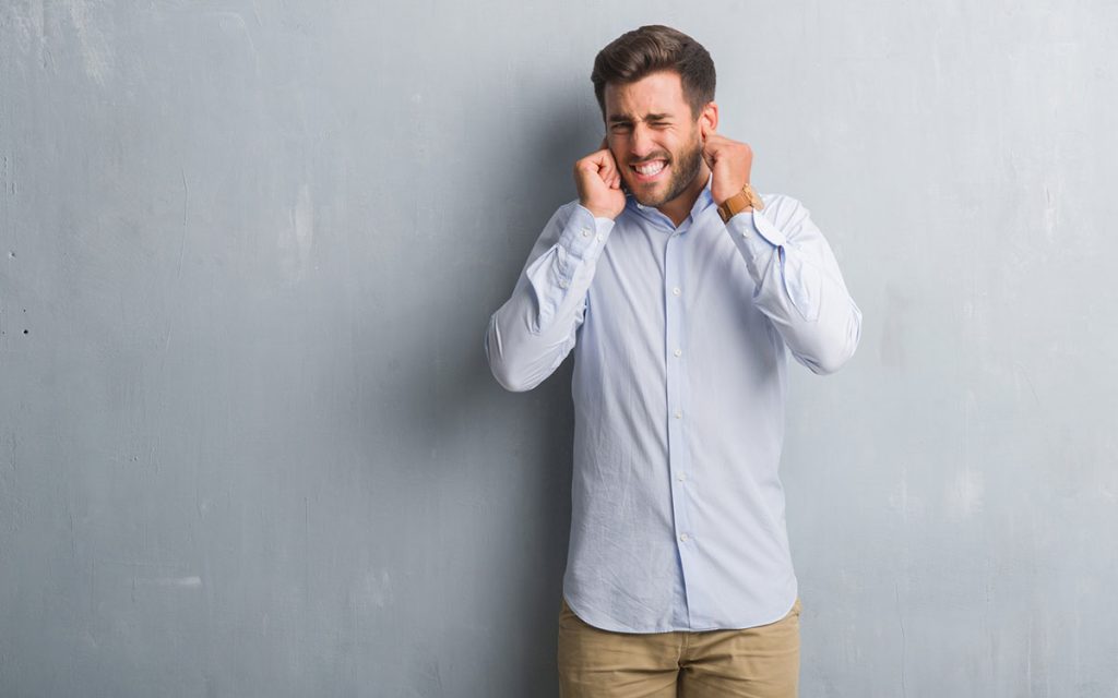 Man with his hands on his ears from wax buildup.
