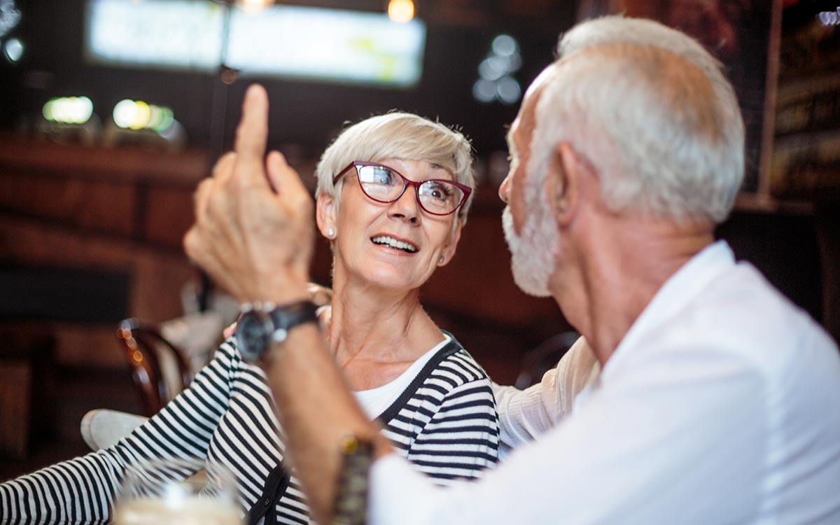 Man and woman trying to hear each other in a noisy restaurant.