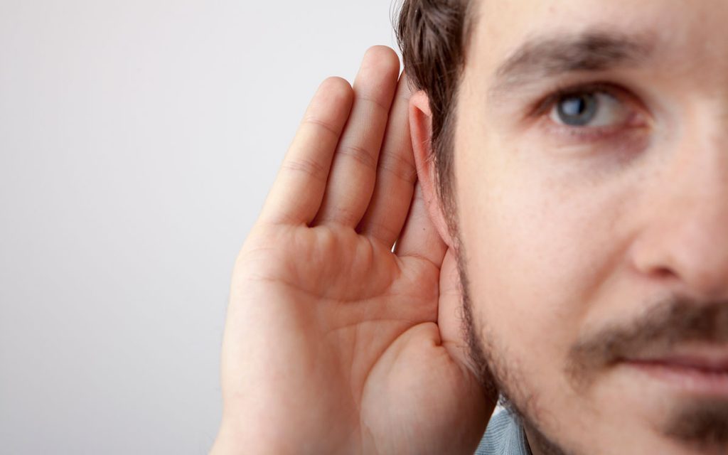 Man with hand to ear discovering many causes of hearing loss.