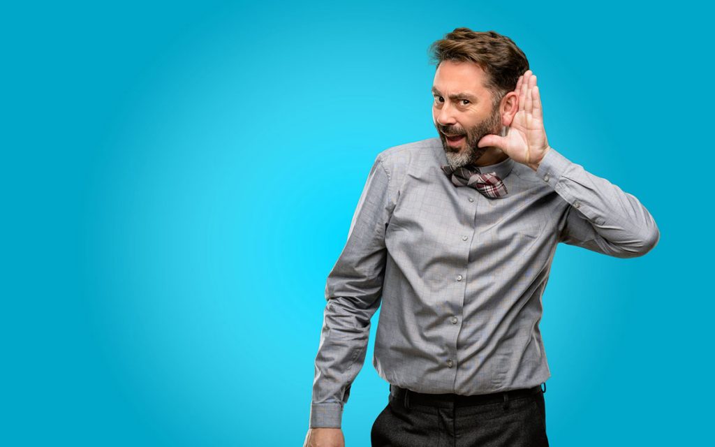 Man with his hand to his ear because he cannot hear even with hearing aids.