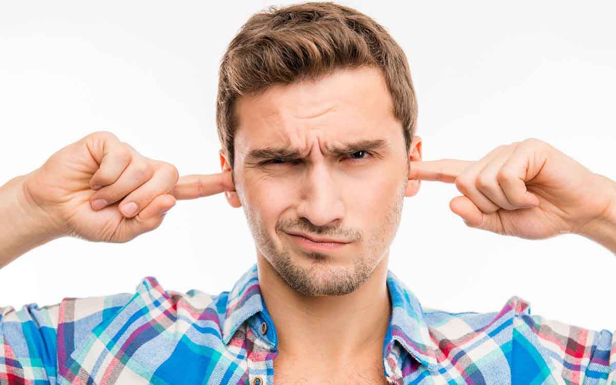 Man with his fingers in his ears symbolizing hearing protection.