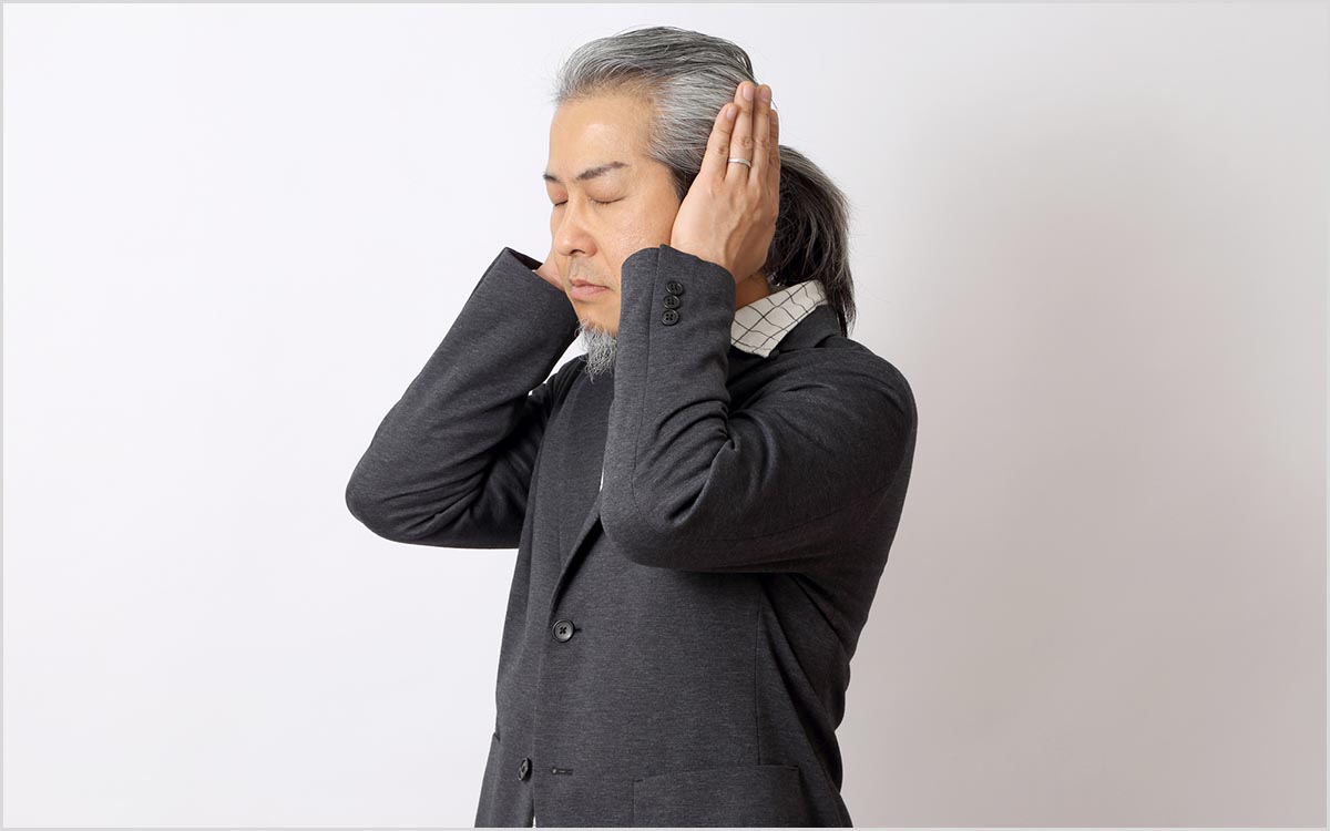 Man with his hand over his ear suffering from Tinnitus and hearing his heartbeat.