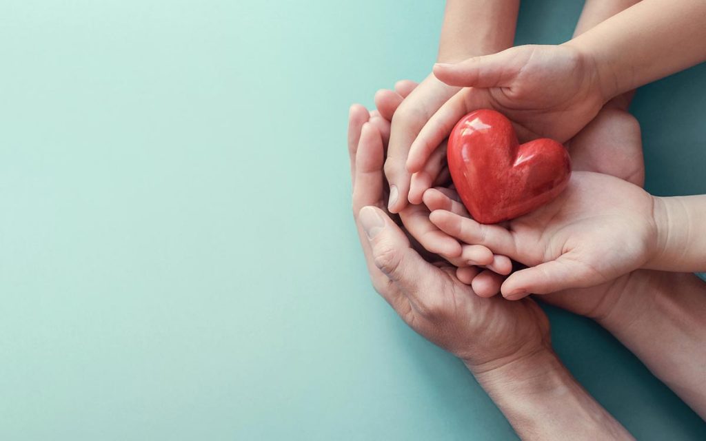 Hands holding a heart representing donating hearing aids.