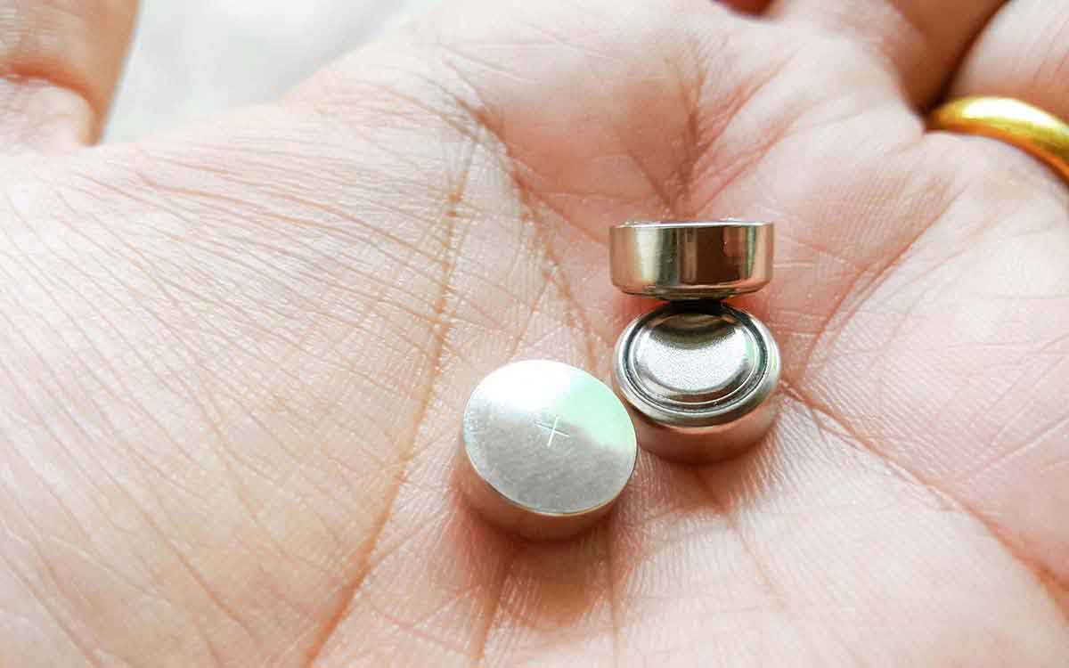 Hand with hearing aid batteries that should be recycled.