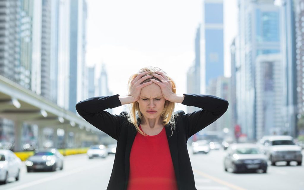 Stressed business woman in the busy city experiencing hearing loss.