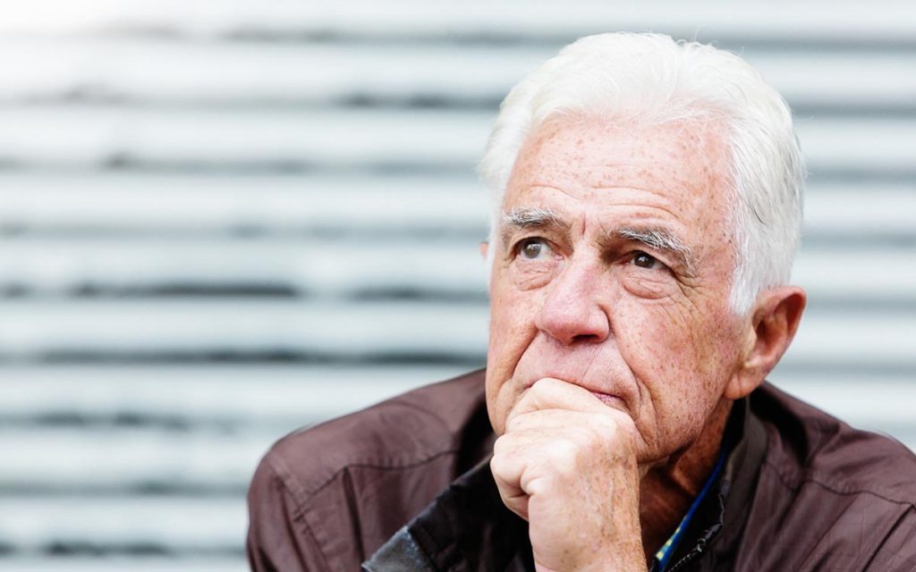 Thoughtful senior man looks serious as he contemplates life suffering from hearing loss and isolation.