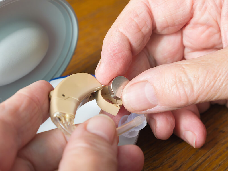Close up of hands changing the battery in a hearing aid