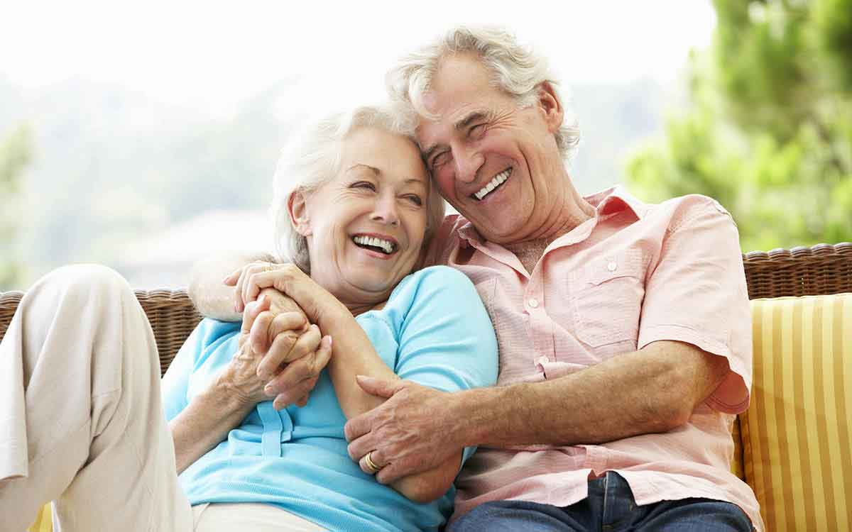 Woman and man cuddling on a park bench after getting hearing aids to improve their relationship.