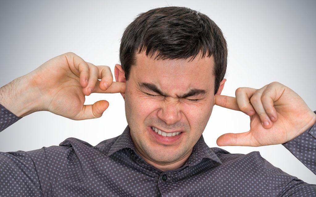 Man closes ears with fingers because of Tinnitus.