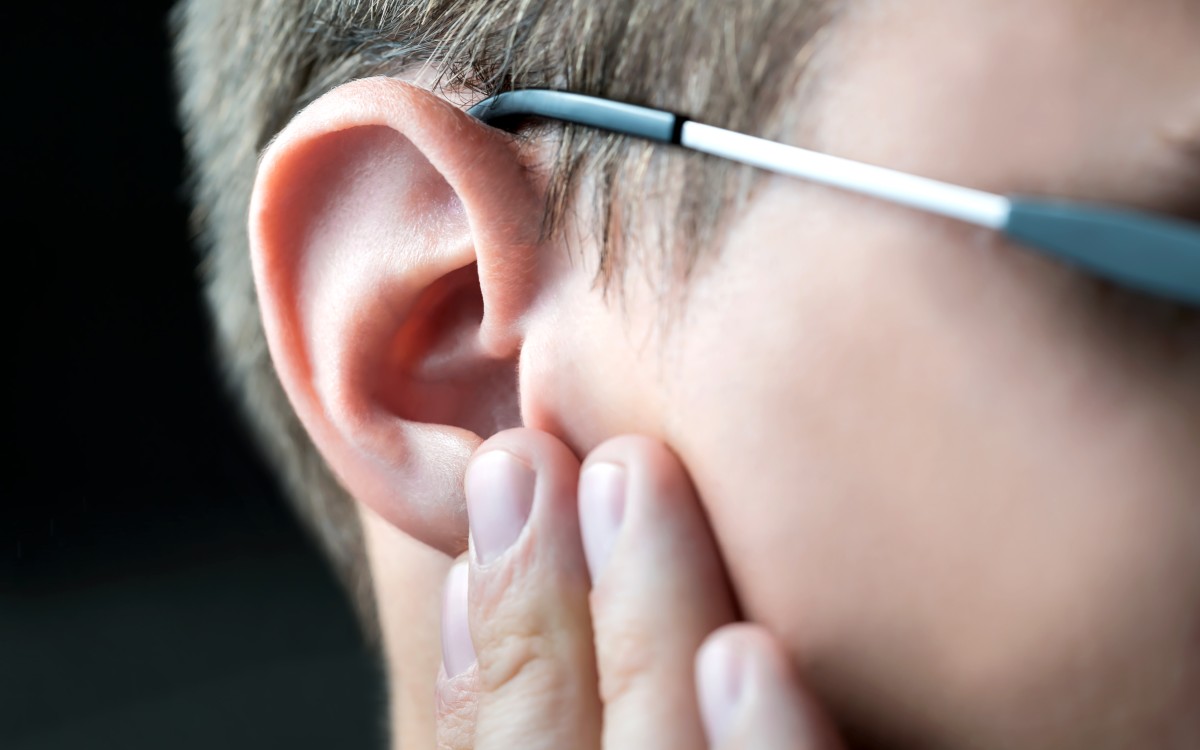 Man holding his ear suffering from otosclerosis.