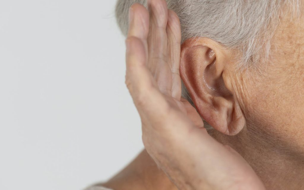 Woman with hand up to ear suffering from singe sided deafness.