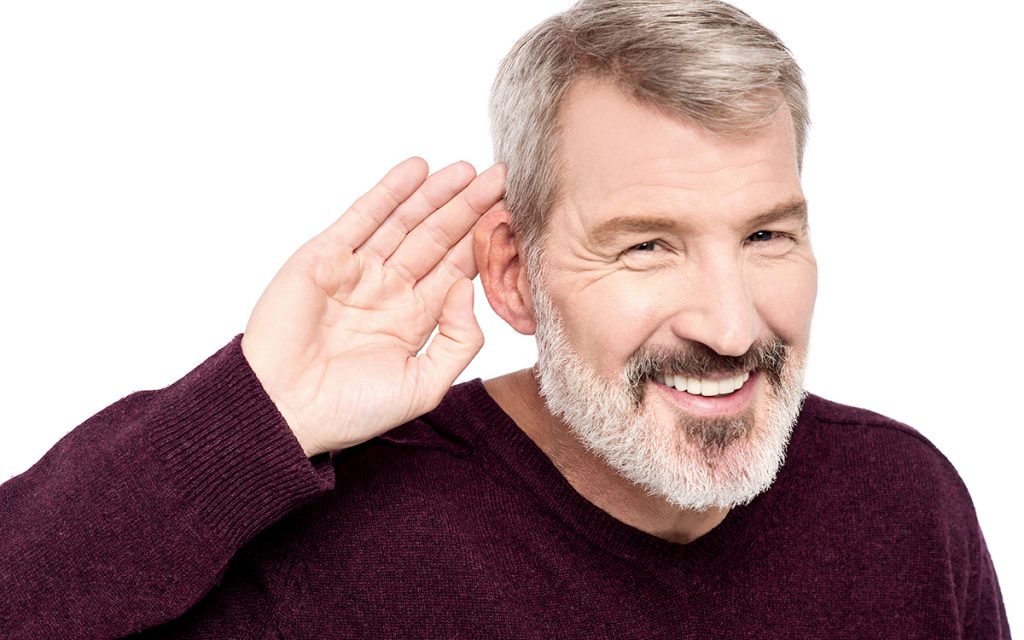 Man with hands to ear becasue of subtle signs of hearing loss.