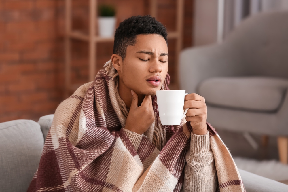 young man with sore throat and tea.