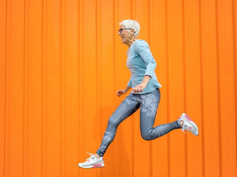 Woman celebrating her new hearing aids by jumping in the air.