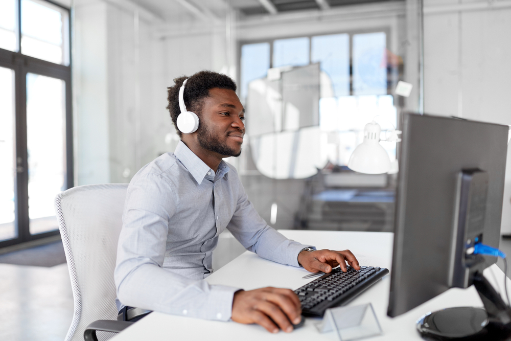 man working in office with headphones on.