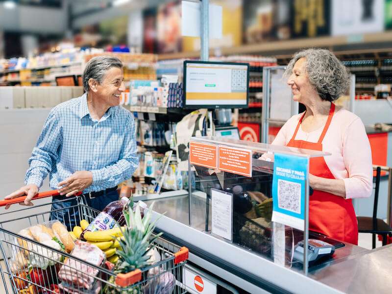 Man talking to grocery cashier and laughing because he hears her.