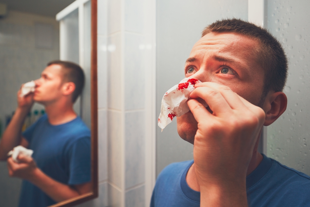 Man with nose bleed in bathroom.
