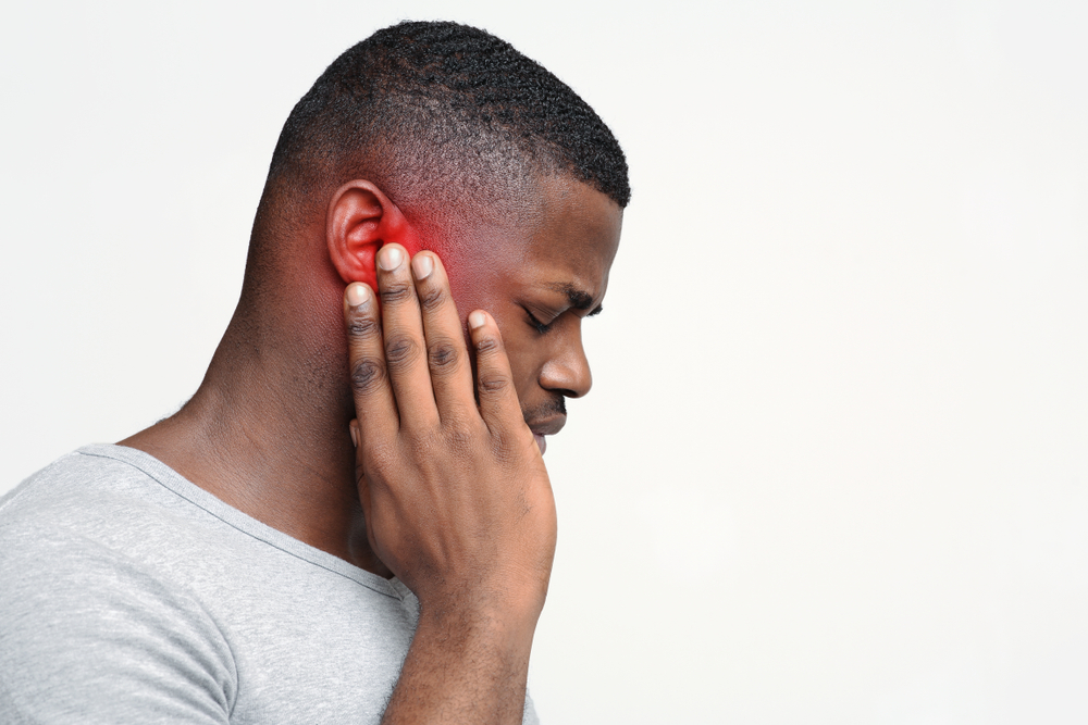 Man holding ear from Tinnitus.