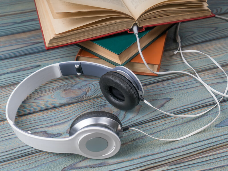 Books with headphones on a wooden table. Concept audiobook, technology, education, listen to books for auditory training.